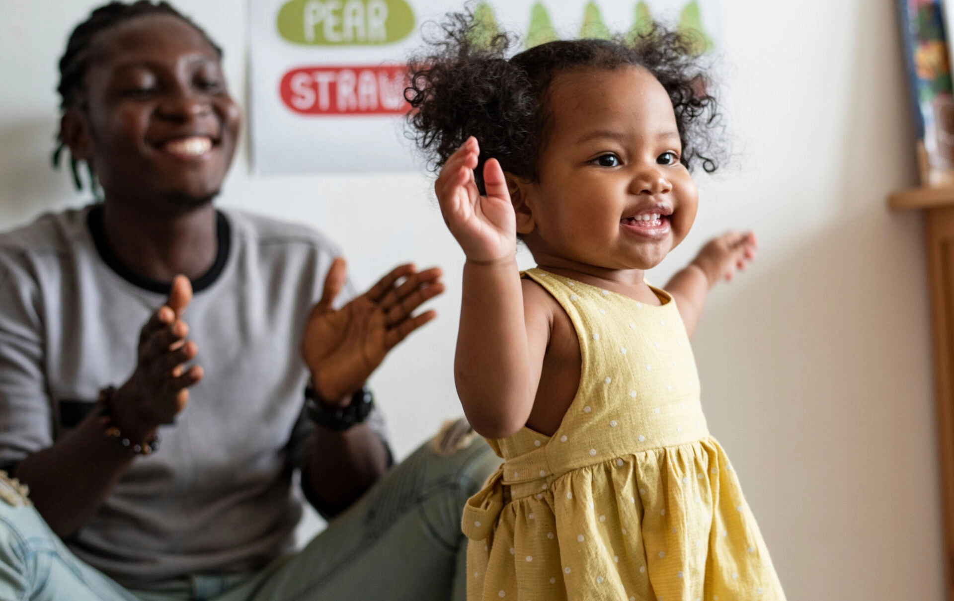 A man claps and cheers a smiling toddler