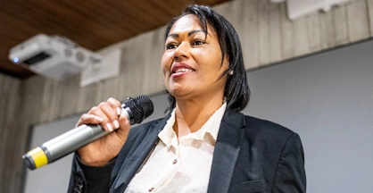 A woman holding a microphone looks out.